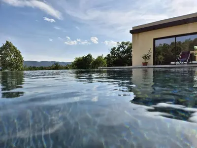 a swimming pool with water in front of a house at Lou damisello - Villa moderne in Viens
