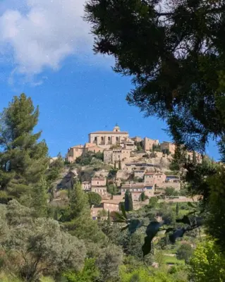a building on top of a hill with trees at Gite la Muscadelle l Isle sur sorgue in LʼIsle-sur-la-Sorgue