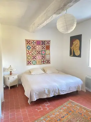 a bedroom with a bed and a table and a lamp at Gite la Muscadelle l Isle sur sorgue in LʼIsle-sur-la-Sorgue