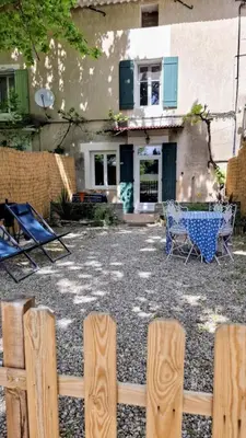a backyard with a table and chairs and a fence at Gite la Muscadelle l Isle sur sorgue in LʼIsle-sur-la-Sorgue