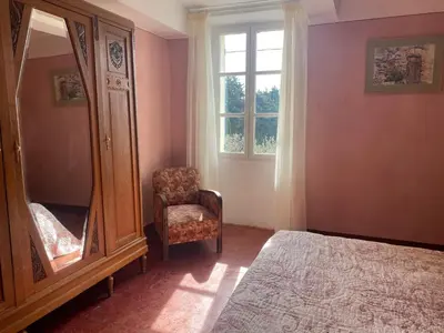 a bedroom with a dresser and a chair and a mirror at Le Rocan Roux in Aubignan