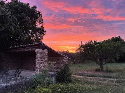 an old stone building in a field with a sunset at Le Rocan Roux in Aubignan
