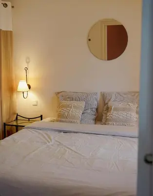 a bed with white sheets and a mirror on the wall at Appartement Nature Golf de Saumane - Vue & Calme in Saumane-de-Vaucluse