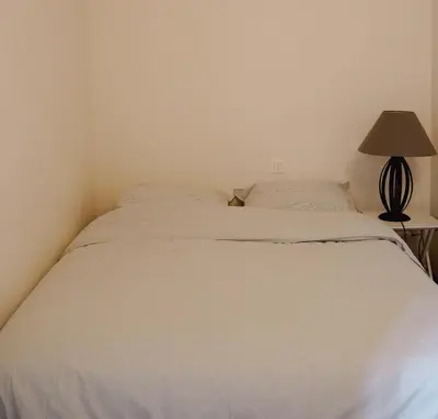 a white bed in a bedroom with a lamp at Appartement Nature Golf de Saumane - Vue & Calme in Saumane-de-Vaucluse