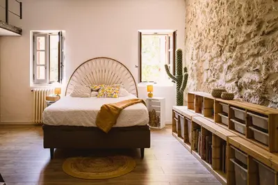 a bedroom with a bed and a large stone wall at Grand Mas Provençal Luberon in Cavaillon