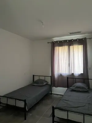 two beds in a room with a window at Villa tout confort en Provence avec Piscine, ainsi qu'un parking privé in Manosque