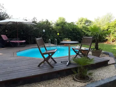 a deck with two chairs and a table next to a pool at La Chambrette in Salon-de-Provence