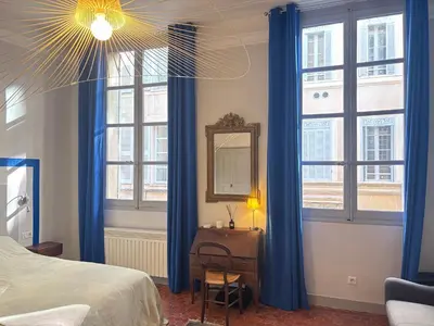 a bedroom with blue curtains and a bed and a mirror at L Appart Aixois in Aix-en-Provence