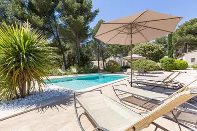 a patio with chairs and an umbrella and a pool at Les Mazets du Luberon in Puget