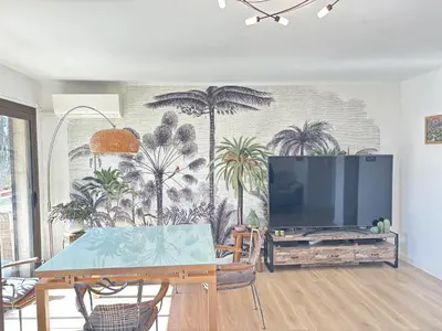 a living room with a tv and a mural of palm trees at Les Cerisiers in Aix-en-Provence
