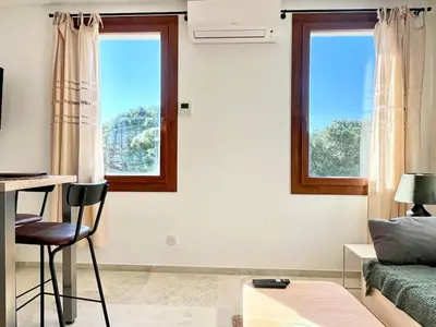 a living room with two windows and a couch at Lou Miradou 1 - Vieux village médiéval, Cosy, Clim, 2 personnes in Miramas