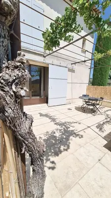 a tree branch next to a building with a table at Domaine des Hauts de Riganel in La Bastide-des-Jourdans