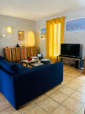 a living room with a blue couch and a television at Chez Mylène et Jean in Bédoin
