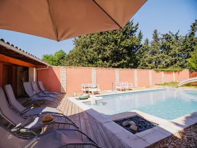 a swimming pool with chairs and purple flowers at Villa provençale avec piscine privée et jardin ensoleillé in Mollégès
