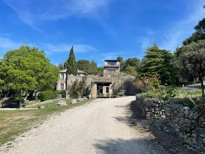 a driveway leading to a large house with a stone wall at Gîte Le Provence Spacieux 100m2 in Saumane-de-Vaucluse