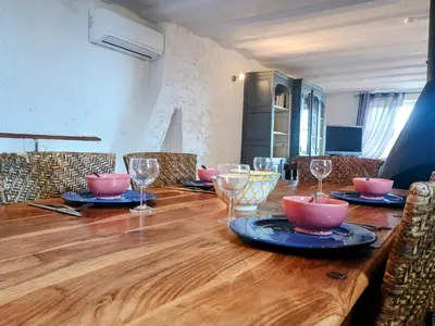 a long wooden table with plates and glasses on it at Gîte Le Provence Spacieux 100m2 in Saumane-de-Vaucluse