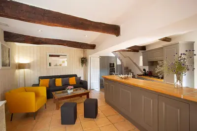 a living room with a yellow couch and a kitchen at Maison Valabregue in Robion en Luberon
