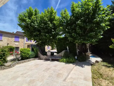 a garden with a tree and a stone patio at Mas Provençal with Swimming Pool & Air Conditioning in Rustrel