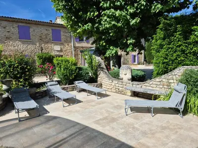 a patio with two benches and a stone wall at Mas Provençal with Swimming Pool & Air Conditioning in Rustrel