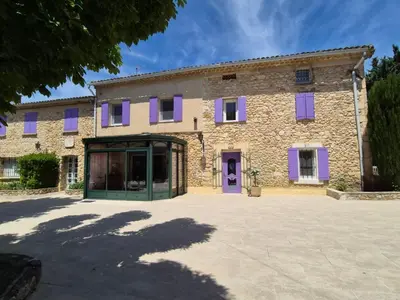 a large stone building with purple shutters at Mas Provençal with Swimming Pool & Air Conditioning in Rustrel