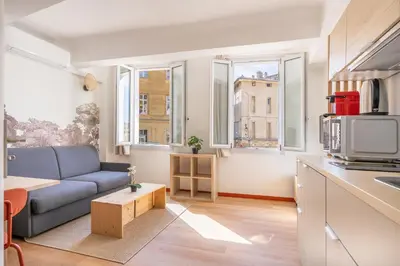 a living room with a blue couch and two windows at Studio climatisé plein centre ville 1er ETAGE in Aix-en-Provence