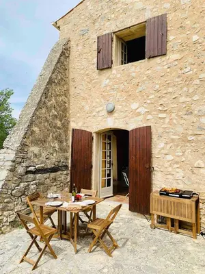 a patio with a table and chairs in front of a building at Provencal farmhouse in Luberon's heart with pool in La Bastide-des-Jourdans