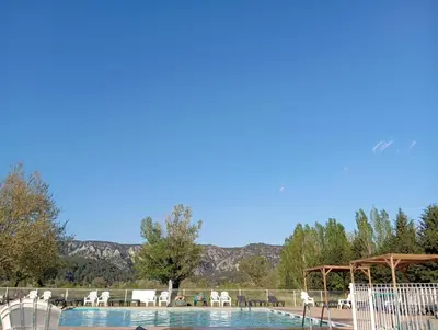 a swimming pool with a gazebo and tables and chairs at Mobil-Home Provence in Cheval-Blanc