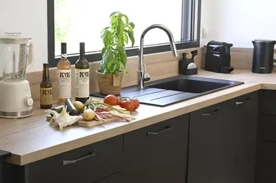 a kitchen counter with a cutting board with vegetables and wine bottles at La Villa Plein Soleil in LʼIsle-sur-la-Sorgue