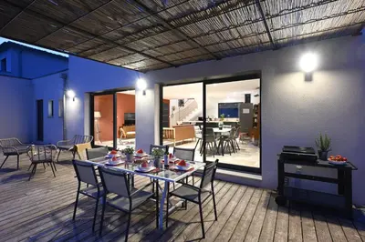 a dining room with a table and chairs on a deck at La Villa Plein Soleil in LʼIsle-sur-la-Sorgue