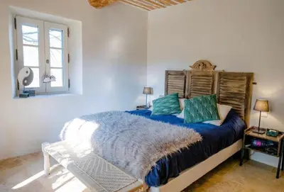 a bedroom with a bed with blue sheets and a window at Mas des Gémeaux in Ménerbes