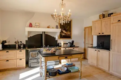 a large kitchen with a table and a chandelier at Mas des Gémeaux in Ménerbes
