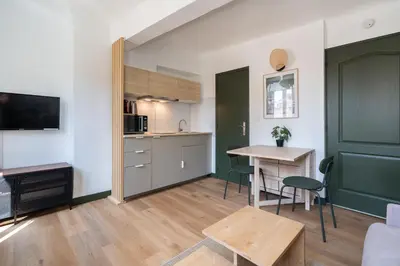 a living room with a table and a kitchen at Studio climatisé plein centre ville 2ème ETAGE in Aix-en-Provence