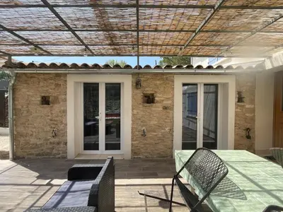 a patio with a table and chairs and a building at La l isloise in LʼIsle-sur-la-Sorgue