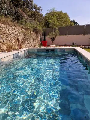 a swimming pool with blue water in a yard at La l isloise in LʼIsle-sur-la-Sorgue