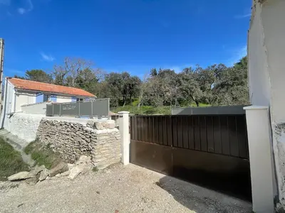 a gate in front of a house with a stone wall at La l isloise in LʼIsle-sur-la-Sorgue