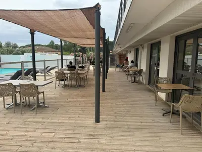 an outdoor patio with tables and chairs and a umbrella at 119 Sous le ciel de Provence - Aix in Éguilles