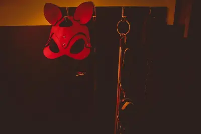 a red mask hanging on a wall in the dark at Osez! Le fruit défendu Loveroom Carpentras in Carpentras
