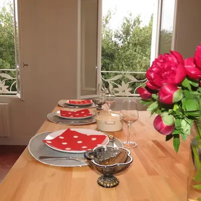 a table with red plates and a vase of red roses at Gorgeous! heart of Aix en Provence appartement climatisé in Aix-en-Provence