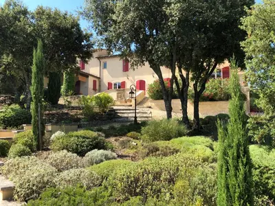 a garden in front of a house with trees and bushes at Le Mas de Quatremonts - Your refuge in Provence in Bonnieux