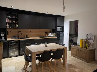 a kitchen with a wooden table and black cabinets at charmante petite maison - piscine hors sol - proche Avignon in Avignon