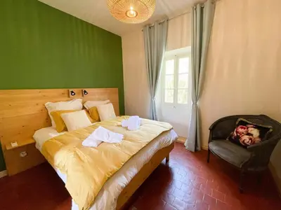 a bedroom with a bed and a chair with a dog on it at House By The Sorgue River With Private Access in Fontaine-de-Vaucluse