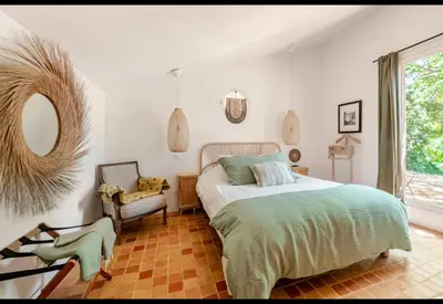 a bedroom with a bed and a chair and a mirror at Bohemian House Overlooking Roussillon in Roussillon