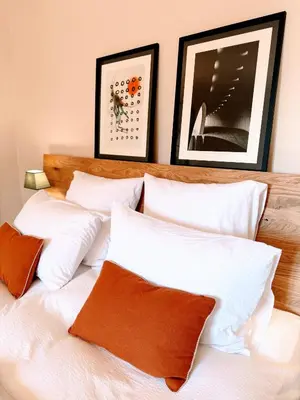 a bed with white pillows and framed pictures on the wall at Les Terrasses de Ventabren in Ventabren