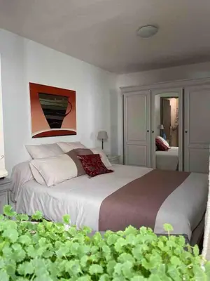 a bedroom with a large bed with a painting on the wall at Appartement de charme au pied du château in Châteaurenard