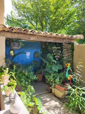 a garden with a blue house with lots of plants at le cabanon du clos in LʼIsle-sur-la-Sorgue