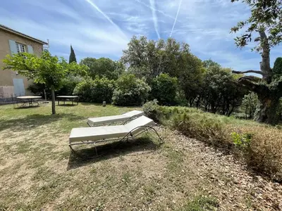 a bench sitting on the grass in a yard at Lubéron Gîte Chaleureux 100 m2 piscine jardin in Saumane-de-Vaucluse