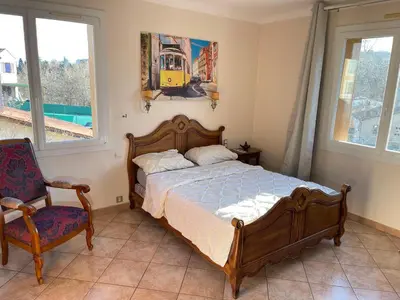 a bedroom with a bed and a chair and windows at Grand Appartement Provençal in Manosque