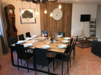 a dining room with a table with chairs and a clock at La Roselière in Mérindol