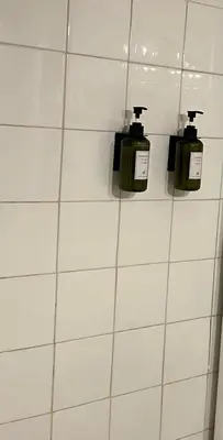 three soap dispensers on a white tiled wall at Studio avec balcon sur cour in Aix-en-Provence
