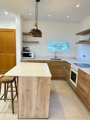 a kitchen with wooden cabinets and a island in it at Le Grand Bouteillan in Pierrevert